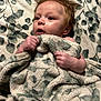 baby, blanket, infant, face, hands, hair, soft_texture, pattern, curious, child, cute, skin, young, portrait, indoors, expression, comfort, warmth, lying_down, person