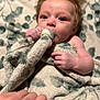 baby, blanket, infant, hand, soft_texture, patterned_blanket, close_up, curious_look, child, indoor, person, face, skin, young_child, nibbling, comfort, warm, cuddly, resting, portrait