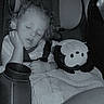 Legend is registered to the contest to win money with this photo: toddler, child, sleeping, car_seat, stuffed_animal, toy, water_bottle, blanket, curly_hair, seatbelt, interior, car, rest, peaceful, young_child, portrait, indoor, cozy, nap, travel