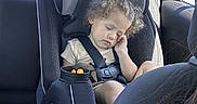 Legend is registered to the contest to win money with this photo: child, toddler, car_seat, sleeping, curly_hair, snack, cup, car_interior, seatbelt, window, sunlight, backseat, safety, young_child, peaceful, relaxed, travel, portrait, casual, daytime