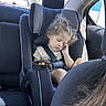 child, toddler, car_seat, sleeping, curly_hair, snack, cup, car_interior, seatbelt, window, sunlight, backseat, safety, young_child, peaceful, relaxed, travel, portrait, casual, daytime