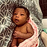 Azariyah is registered to the contest to win money with this photo: baby, infant, blanket, pink, patterned_fabric, geometric_pattern, face, eyes, hand, skin, newborn, cute, portrait, cozy, soft_texture, indoors, lying_down, resting, expression, child