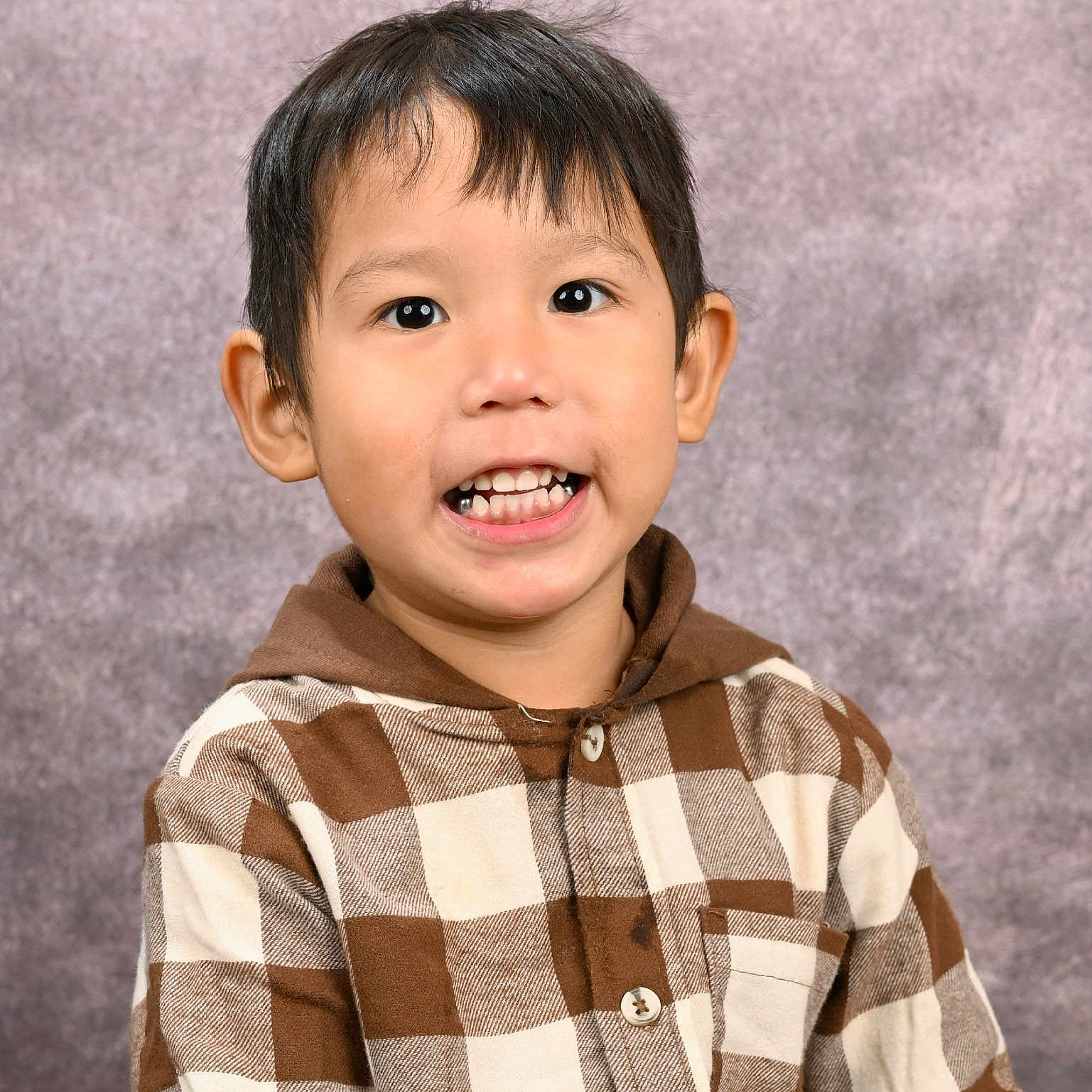 Lucius is registered to the contest to win money with this photo: boy, brown_hair, buttoned_shirt, casual_clothing, checkered_shirt, child, cute, expression, face, happy, head_and_shoulders, hoodie, indoor, light_skin, person, portrait, smiling, studio_background, teeth, young