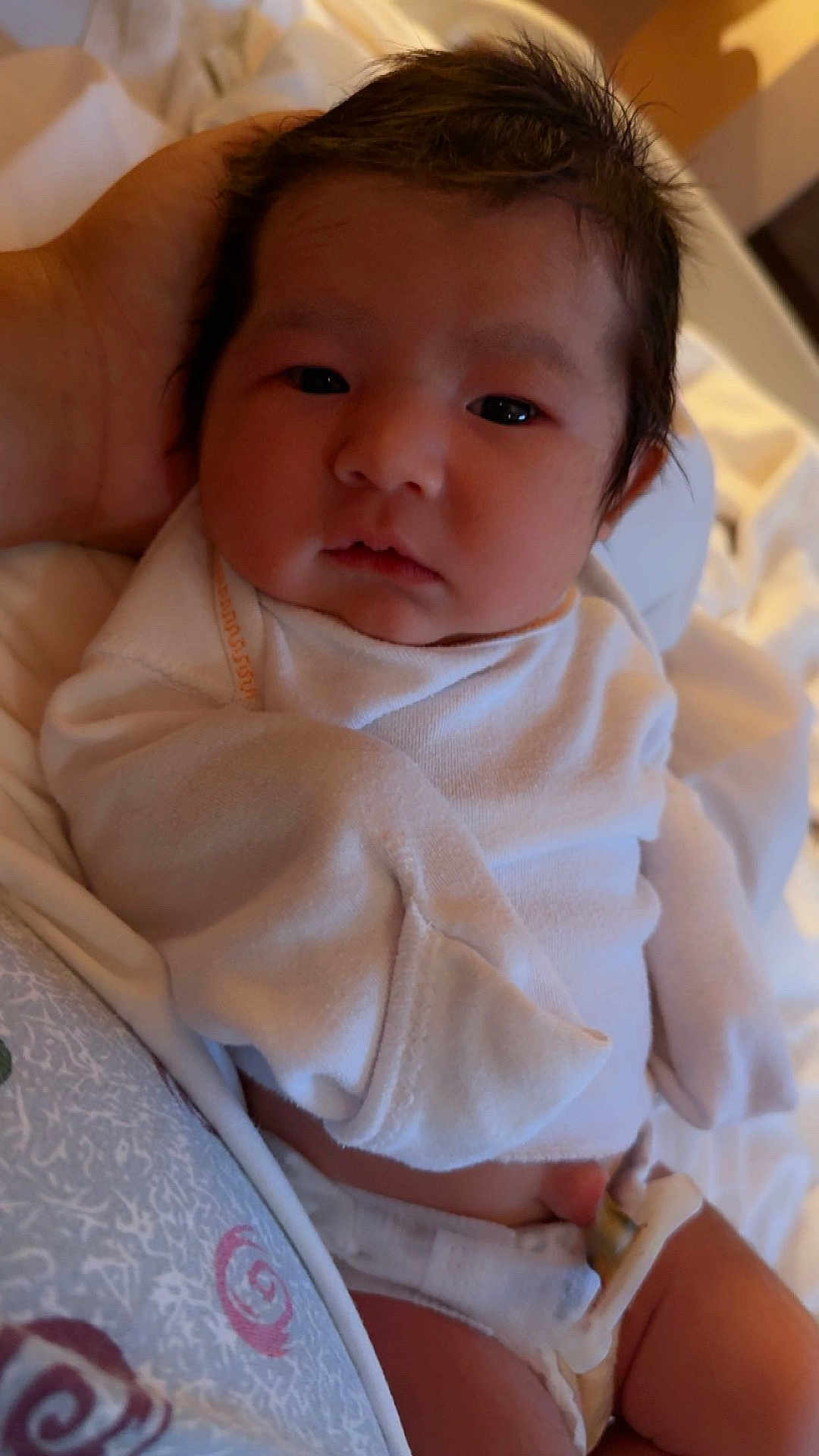 Elaine joined the competition — help win amazing prizes! baby, newborn, infant, white_clothing, diaper, hand, bed, blanket, sleepwear, person, cute, soft_light, indoors, resting, face, skin, hair, expression, comfort, peaceful