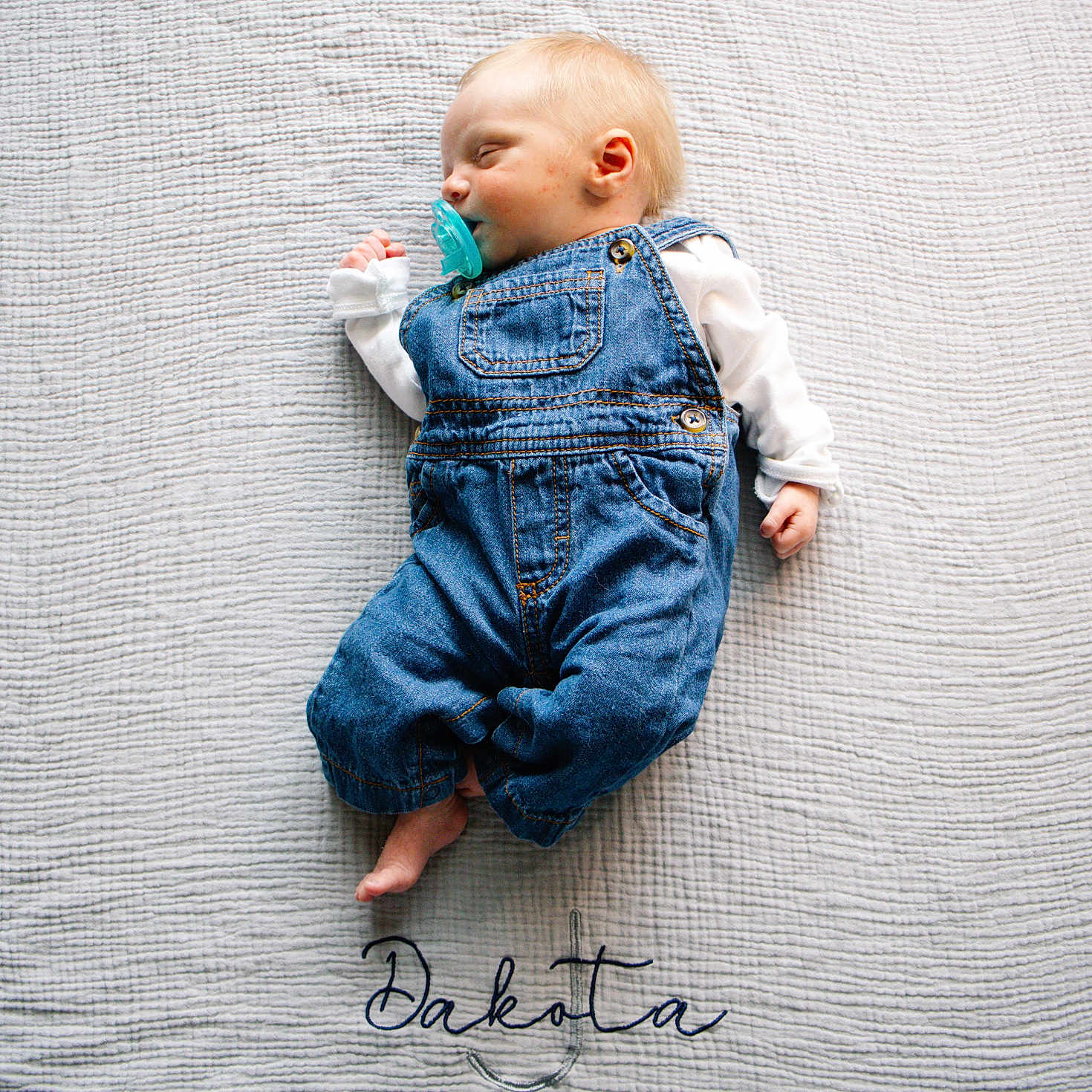 Dakota is registered to the contest to win money with this photo: baby, sleeping, pacifier, denim_overalls, white_blanket, textured_blanket, infant, cute, resting, child, portrait, peaceful, soft_lighting, indoors, cozy, small_hands, small_feet, name_embroidery, calm, sleep