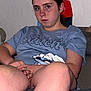person, child, tshirt, blue_clothing, sitting, indoor, couch, hands_folded, legs, serious_expression, freckles, earring, casual, relaxed, young_person, wall, household_item, shorts, portrait, looking_at_camera