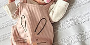 Gracie is registered to the contest to win money with this photo: baby, infant, pacifier, pink_clothing, headwrap, bunny_design, blanket, white, cute, sleepwear, portrait, child, soft_light, indoors, small_hands, texture, laying_down, cozy, adorable, face