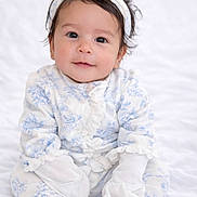 Khaleessi joined the competition — help win amazing prizes! baby, infant, child, pajamas, mittens, headband, flower, sitting, white_background, soft_texture, cute, portrait, indoors, smiling, young_child, clothing, cozy, looking_at_camera, face, adorable