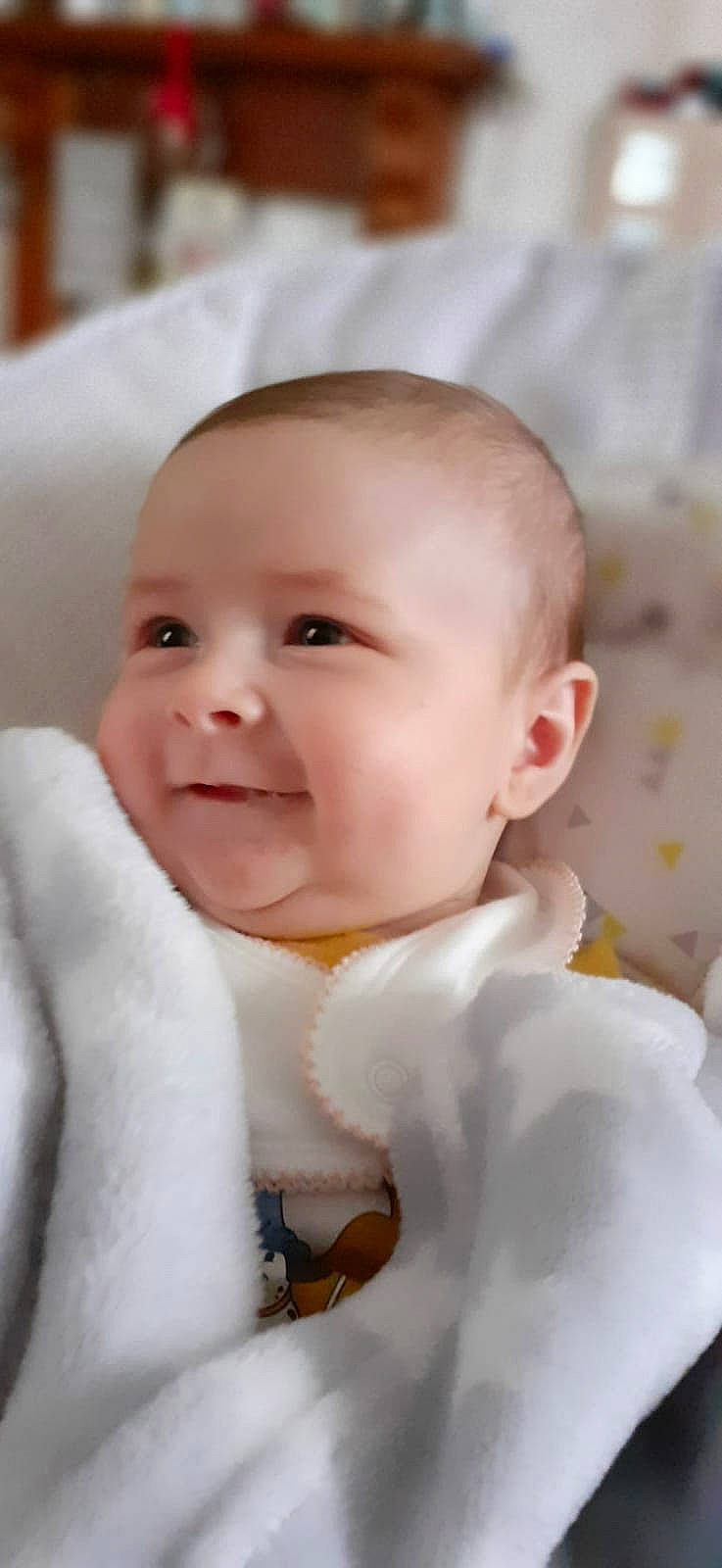 Elly is registered to the contest to win money with this photo: baby, baby_toddler_clothing, cheek, child, collar, comfort, eyebrow, eyelash, formal_wear, happy, iris, joy, lip, pattern, peach, person, portrait_photography, sitting, skin, sleeve