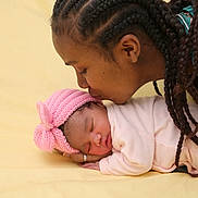 Nely a rejoint le concours — aidez-le/la à gagner de superbes lots ! adult, affection, baby, braids, close_up, family_moment, hand, infant, kiss, knit_hat, newborn, peaceful, pink_hat, portrait, ring, sleeping, soft_lighting, studio_background, swaddle, yellow_background