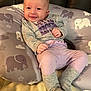 Carson is registered to the contest to win money with this photo: baby, smile, infant, clothing, pillow, elephant_pattern, socks, purple, gray, cute, happy, face, person, indoor, soft, blanket, seated, child, toddler, cozy