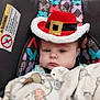 baby, infant, car_seat, hat, red_hat, blanket, pacifier, butterfly_pattern, child, indoor, retail_store, seat_belt, cute, face, person, clothing, winter_wear, expressionless, headwear, baby_accessory
