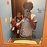 Dakota Haile joined the competition — help win amazing prizes! baby, infant, child, teenager, mirror_selfie, bathroom, phone, smartphone, portrait, family, caregiver, sitting, holding, white_clothing, satin, bib, socks, mirror, sink, indoor