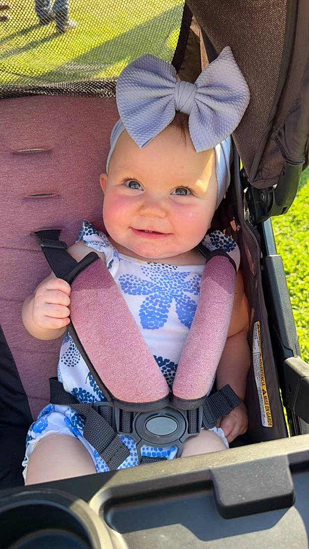 Juliana is registered to the contest to win money with this photo: auto_part, baby, baby_carriage, baby_products, baby_safety, baby_toddler_clothing, child, electric_blue, fashion_accessory, fun, happy, hat, headwear, joy, person, pink, purple, sitting, skin, smile