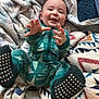 Hayes joined the competition — help win amazing prizes! baby, child, smiling, pajamas, green, christmas_tree_pattern, blanket, soft_texture, cozy, happy, indoor, footwear, socks, reaching_hands, face, infant, cute, playful, lying_down, warm