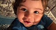 Zamariel joined the competition — help win amazing prizes! baby, blue_shirt, child, close_up, curly_hair, cushion, cute, expression, eyes, face, happy, head, indoors, patterned_fabric, person, portrait, skin, smiling, toddler, young_child