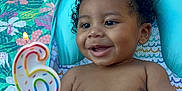 Marcel is registered to the contest to win money with this photo: baby, child, smiling, curly_hair, birthday_candle, number_6_candle, diaper, bracelet, baby_seat, blanket, outdoor, grass, hand, person, happy, celebration, colorful, cute, infant, portrait