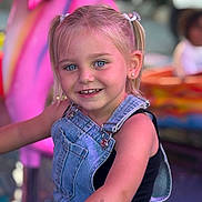 Luna a rejoint le concours — aidez-le/la à gagner de superbes lots ! child, girl, smiling, blue_eyes, blonde_hair, pigtails, denim_overalls, black_tank_top, tattoo, earrings, outdoor, amusement_park, carnival, colorful_background, portrait, happy, young, face, person, playful