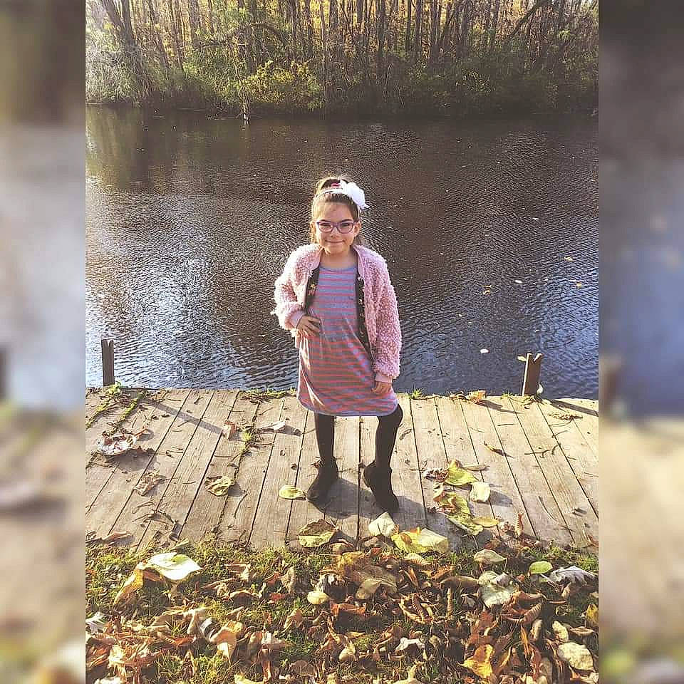 Madalynn is registered to the contest to win money with this photo: adaptation, autumn, branch, child, forest, grass, joy, leaf, outerwear, people_in_nature, person, photography, plant, smile, standing, tree, water