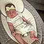baby, infant, sleeping, headband, bow, cushioned_lounger, white_outfit, fruit_print, cozy, comfortable, couch, fabric, soft_lighting, peaceful, child, person, indoor, relaxing, cute, newborn