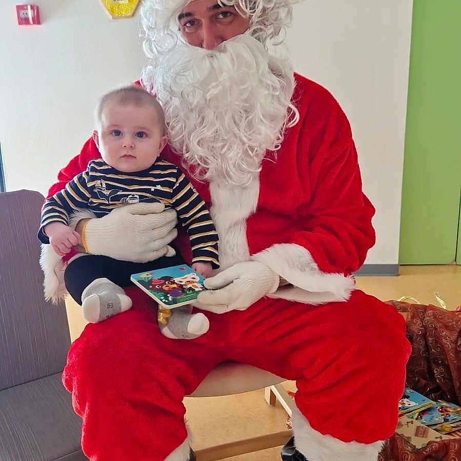 Owen a rejoint le concours — aidez-le/la à gagner de superbes lots ! baby, beard, book, boots, chair, child, clock, costume, decorations, floor, gloves, holiday, indoor, person, red_clothing, santa_claus, smile, striped_clothing, toy, wall