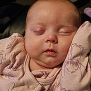 Zoe is registered to the contest to win money with this photo: baby, sleeping, infant, face, pink_clothing, cartoon_print, cozy, peaceful, resting, closeup, skin, person, child, cute, newborn, soft, indoors, portrait, young, calm