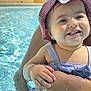 Aleyna a rejoint le concours — aidez-le/la à gagner de superbes lots ! adult_arm, baby, child, closeup, cute, fun, happy, holding, outdoor, person, playful, pool, skin, smiling, summer, sun_hat, sunlight, swimsuit, vacation, water