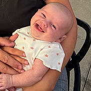 Summer joined the competition — help win amazing prizes! baby, smiling, infant, person, arm, hand, clothing, white_shirt, pink_flowers, happy, cute, skin, face, head, sitting, holding, outdoor, chair, joyful, closeup