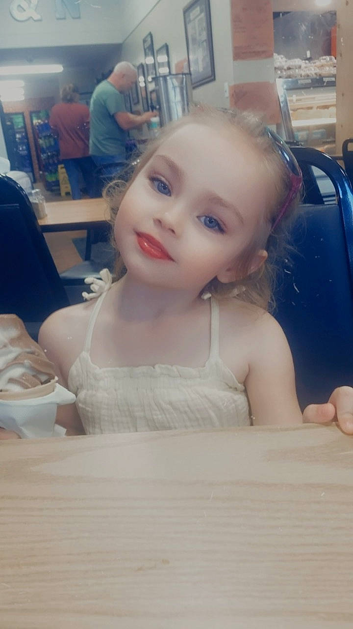 Isabella is registered to the contest to win money with this photo: blond, chair, cheek, chin, dress, eyebrow, eyelash, flooring, fun, happy, iris, nose, person, shoulder, sitting, skin, smile, table, tableware, toddler