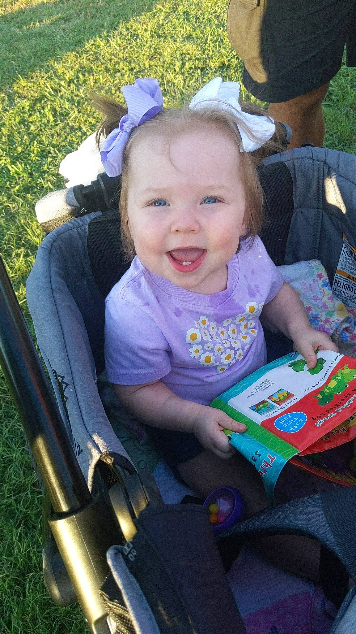 Evie is registered to the contest to win money with this photo: baby, baby_carriage, baby_toddler_clothing, blue, child, event, face, fun, grass, happy, hat, joy, lap, leisure, person, photograph, plant, recreation, sitting, smile