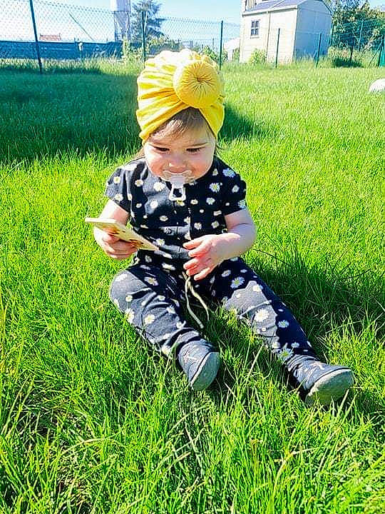 Giulia a rejoint le concours — aidez-le/la à gagner de superbes lots ! baby, boot, fun, grass, grassland, happy, hat, headwear, joy, landscape, lawn, leisure, pattern, people_in_nature, person, personal_protective_equipment, plant, prairie, recreation, sitting