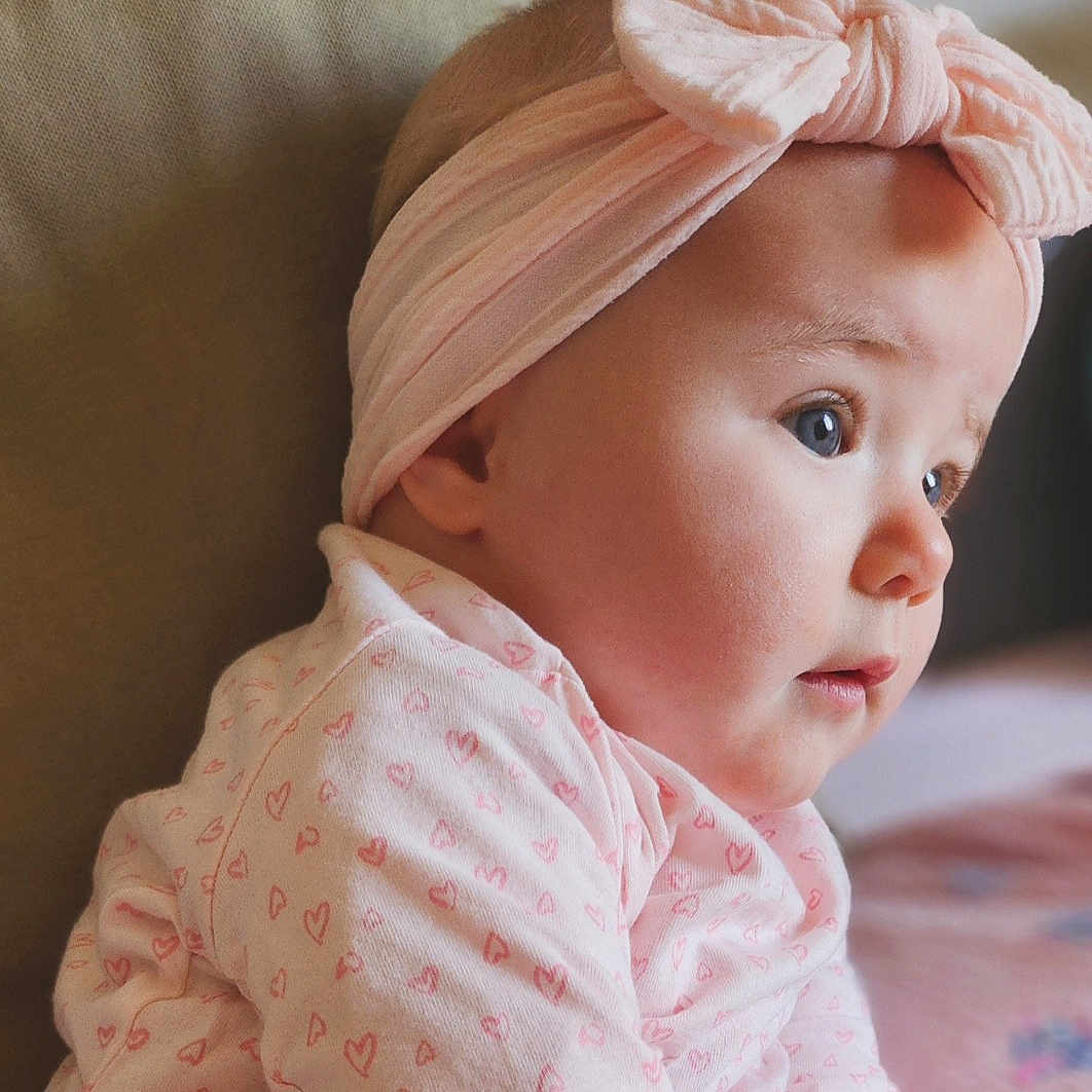 Peyton a rejoint le concours — aidez-le/la à gagner de superbes lots ! adorable, baby, bow, child, closeup, clothing, cute, face, gaze, headband, heart_pattern, indoors, infant, pink, portrait, profile, skin, soft, warm, young