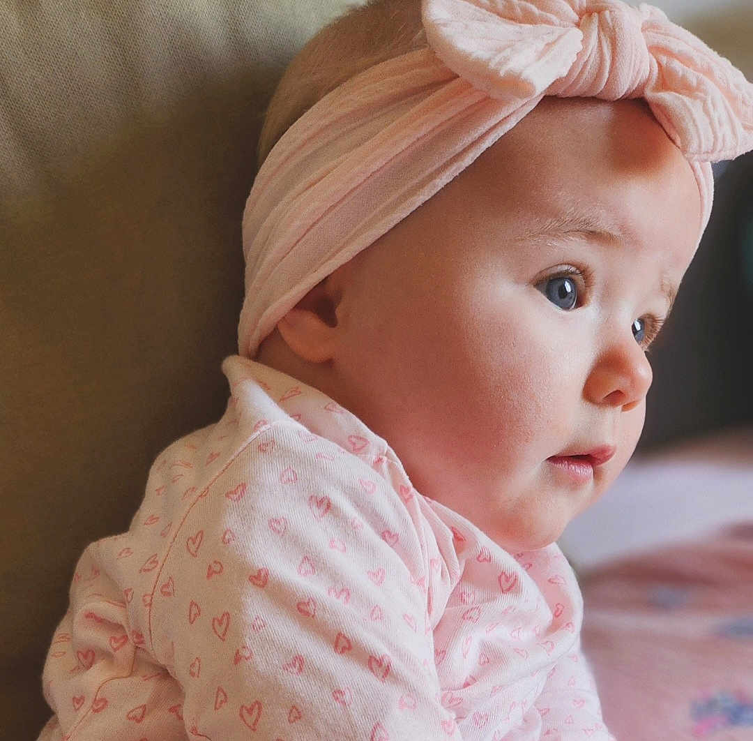 Peyton a rejoint le concours — aidez-le/la à gagner de superbes lots ! baby, infant, headband, pink, bow, clothing, face, profile, cute, child, young, soft, adorable, heart_pattern, closeup, portrait, skin, gaze, indoors, warm