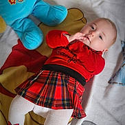 Peyton a rejoint le concours — aidez-le/la à gagner de superbes lots ! baby, child, plush_toy, blanket, red_sweater, plaid_skirt, white_tights, cartoon_characters, floor, cute, indoors, toy, lying_down, toddler, soft_toy, warm_clothing, cozy, childrens_room, smiling, baby_girl