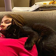 Jill is registered to the contest to win money with this photo: child, black_cat, couch, indoor, snuggling, red_shirt, relaxing, pet, animal, furniture, home, cozy, face, resting, cute, domestic_cat, young, comfort, leisure, warm
