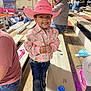 Karter joined the competition — help win amazing prizes! child, smiling, cowboy_hat, pink_hat, pink_shirt, jeans, boots, bleachers, crowd, indoor, event, rodeo, wooden_floor, people, spectators, thumbs_up, casual_clothing, happy, portrait, family_event