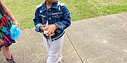 Karter is registered to the contest to win money with this photo: child, girl, denim_jacket, white_bow, curly_hair, sidewalk, grass, parked_cars, colorful_dress, boots, outdoor, holding, serious_expression, summer_clothing, fashion, person, portrait, daytime, casual, suburban