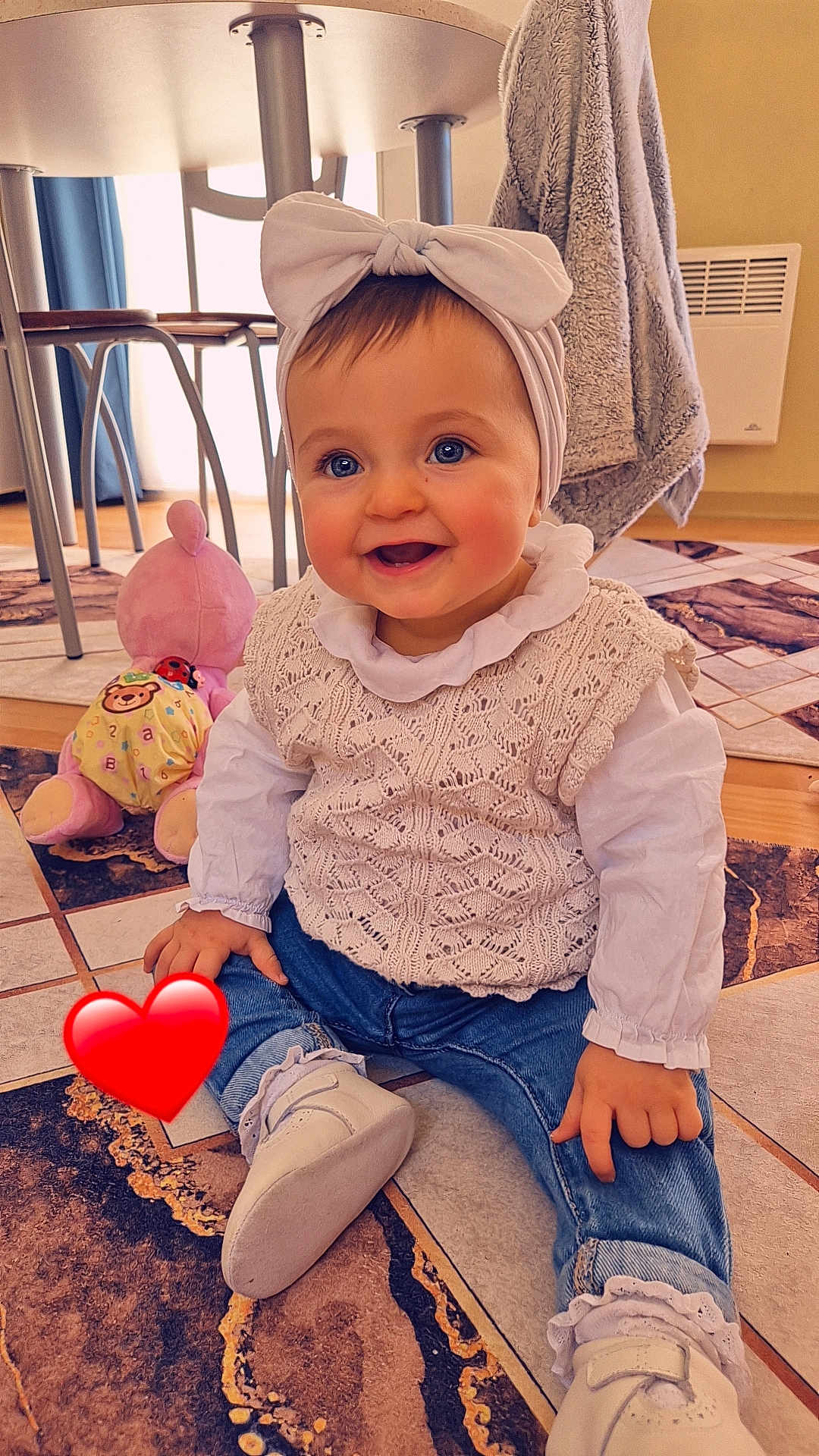 Ilyana participe au concours pour gagner de l'argent avec cette photo : baby, child, smiling, blue_eyes, headband, bow, knitted_vest, white_blouse, jeans, socks, shoes, toy, plush_toy, floor_tiles, indoor, furniture, curtain, heater, happy, portrait