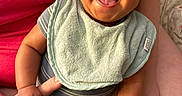 Giuseppe is registered to the contest to win money with this photo: adult, baby, bib, clothing, cute, face, hand, happy, holding, indoor, infant, person, portrait, red_shirt, seated, skin, smiling, socks, striped_outfit, tongue_out