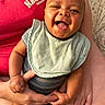 adult, baby, bib, clothing, cute, face, hand, happy, holding, indoor, infant, person, portrait, red_shirt, seated, skin, smiling, socks, striped_outfit, tongue_out