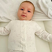 éléa participe au concours pour gagner de l'argent avec cette photo : baby, infant, white_clothing, heart_pattern, sweater, pants, lying_down, soft_surface, cute, face, eyes, buttoned_sweater, child, portrait, indoors, young_child, comfort, expression, small, person
