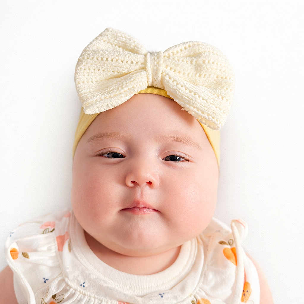 Yeshua is registered to the contest to win money with this photo: baby, infant, portrait, headband, bow, chubby_cheeks, close_up, white_background, onesie, cute, soft_skin, studio_light, neutral_expression, face, eyes, adorable, baby_clothing, fruit_print, round_face, sleepy_look