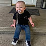 Drew joined the competition — help win amazing prizes! baby, child, pacifier, black_tshirt, jeans, sneakers, concrete, steps, door, outdoor, smiling, cute, young_child, clothing, footwear, person, front_door, curious, happy, sitting