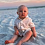 baby, child, sand, beach, sunset, white_shirt, barefoot, blue_eyes, cute, outdoor, sitting, infant, sky, pastel_colors, nature, portrait, soft_light, summer, vacation, curious
