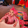 baby, baby_walker, carpet, child, christmas_tree, colorful, curtain, dog_paws, face, furniture, headband, indoor, living_room, pajamas, person, pink_bow, play_mat, smiling, toy, window