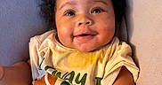 Ahsai is registered to the contest to win money with this photo: baby, casual, child, cozy, curly_hair, cute, expression, face, hand, happy, indoors, infant, person, portrait, shirt, sitting, skin, smiling, stain, young