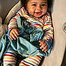 baby, child, smiling, curly_hair, striped_pajamas, blanket, cushioned_seat, indoor, comfort, cute, happy, infant, toddler, person, portrait, cozy, resting, soft_texture, warm, playful