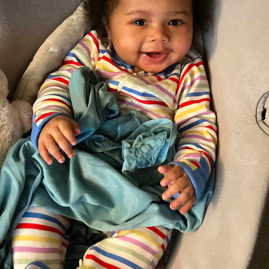 Ahsai joined the competition — help win amazing prizes! baby, child, smiling, curly_hair, striped_pajamas, blanket, cushioned_seat, indoor, comfort, cute, happy, infant, toddler, person, portrait, cozy, resting, soft_texture, warm, playful