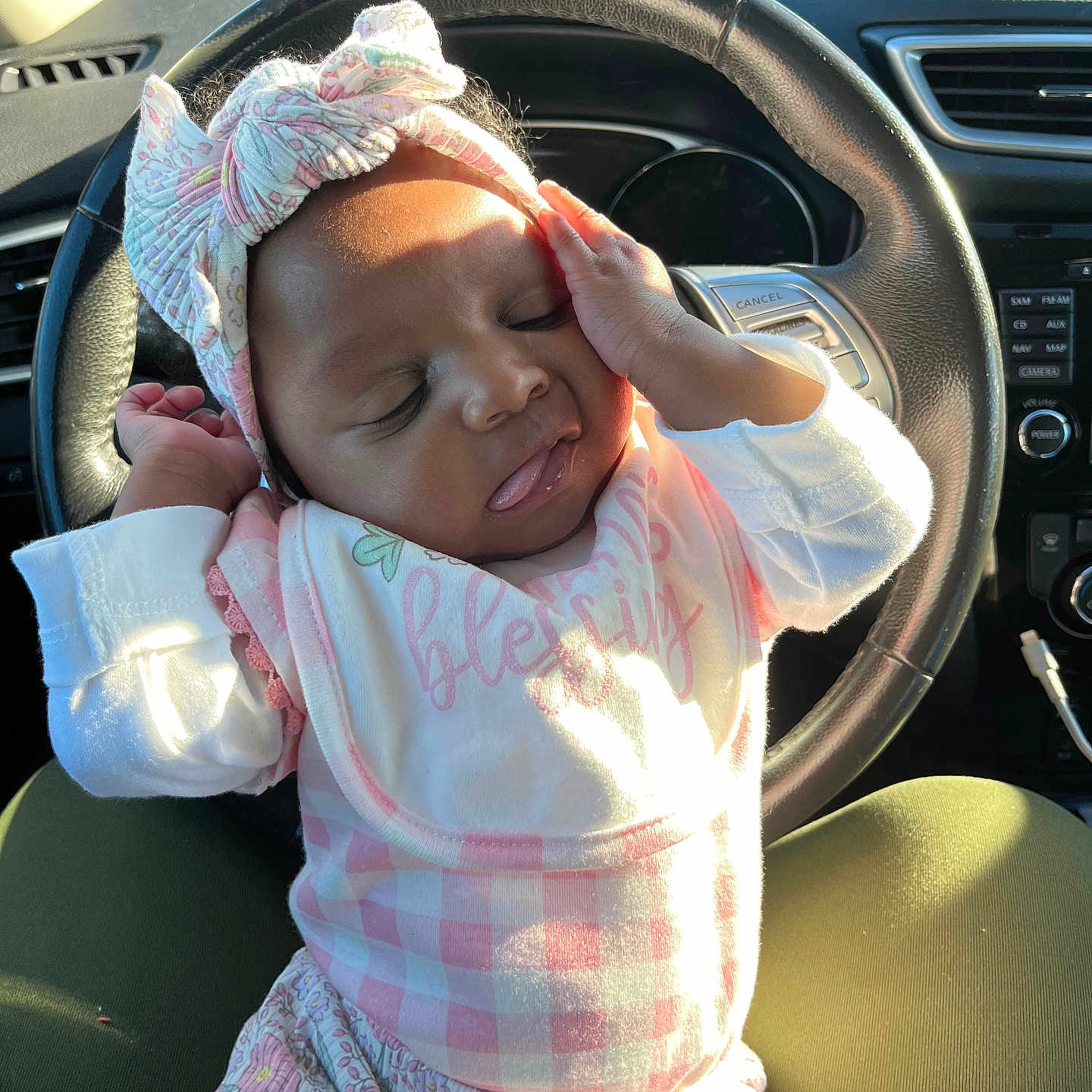 Ka Leyah is registered to the contest to win money with this photo: baby, bib, bow, car_interior, child, clothing, cute, hand, headband, infant, lap, pattern, person, pink, portrait, relaxing, seat, sleepy, steering_wheel, sunlight