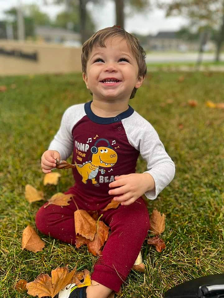 Oliver is registered to the contest to win money with this photo: baby, baby_toddler_clothing, child, face, fun, grass, happy, joy, lawn, leaf, people_in_nature, person, plant, play, recreation, sitting, sleeve, smile, soil, t_shirt